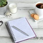 high-angle-view-of-a-blank-notepad-journal-diary-on-a-light-wooden-desk-or-table-overhead-flat-lay_t20_B8lKGv